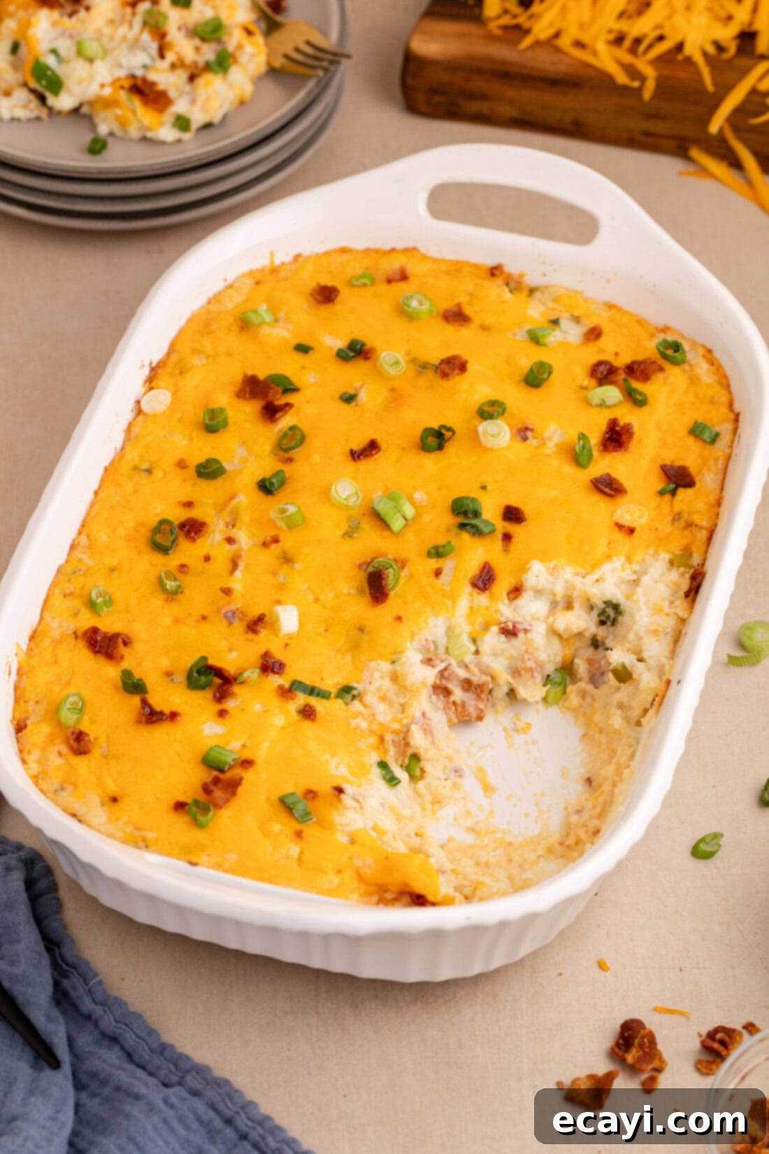 Loaded Cheesy Potato Casserole 14 Twice Baked Potato Casserole with a serving removed, showcasing its creamy interior and cheesy top