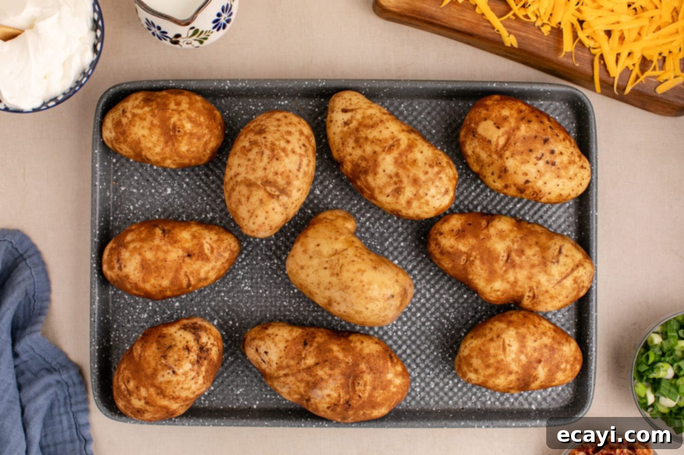 Loaded Cheesy Potato Casserole 5 russet potatoes with fork piercings on a baking sheet, ready for baking