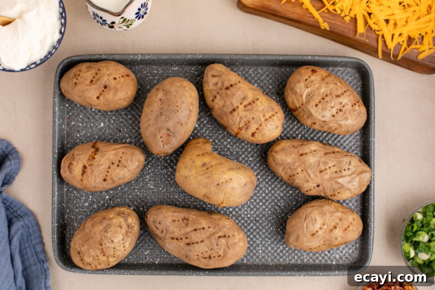 Loaded Cheesy Potato Casserole 6 baked russet potatoes cooling on a baking sheet after being removed from the oven
