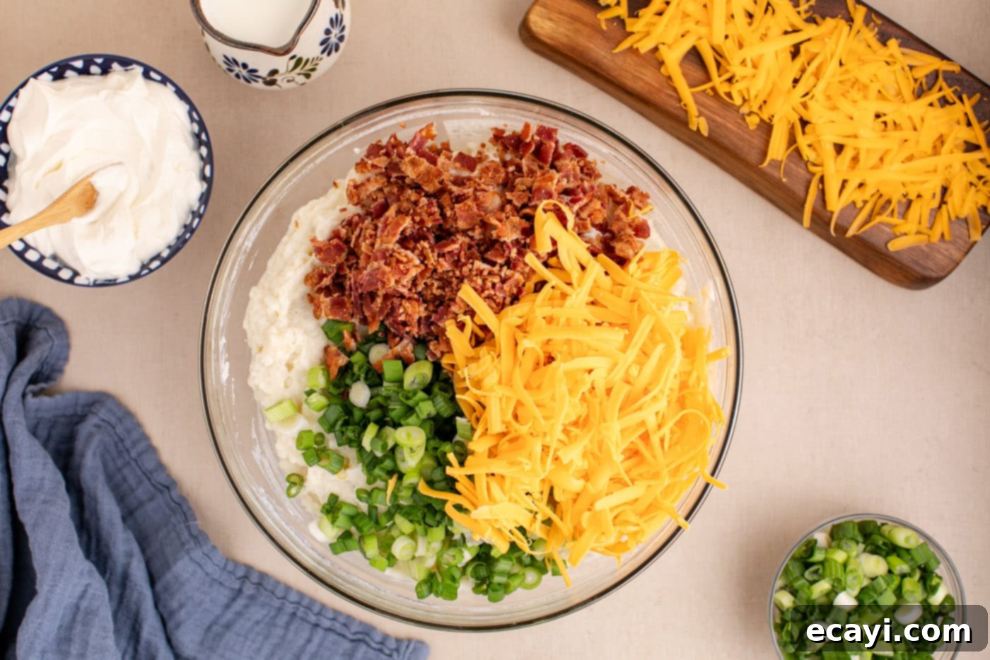 Loaded Cheesy Potato Casserole 9 crumbled bacon, shredded cheddar cheese, and sliced green onion being folded into the creamy potato filling