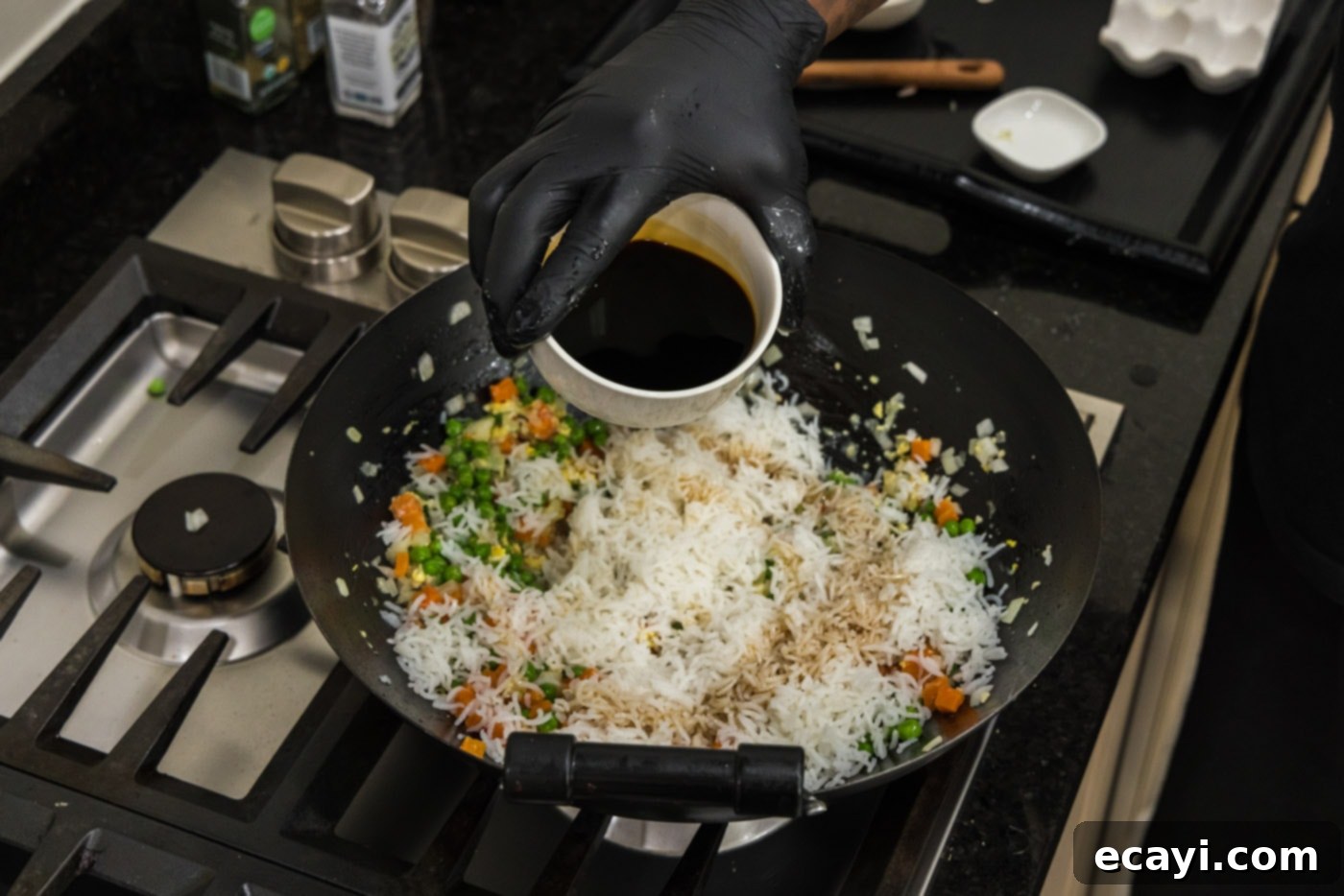 Golden Shrimp Fried Rice 13 pouring soy sauce into wok with rice and vegetables