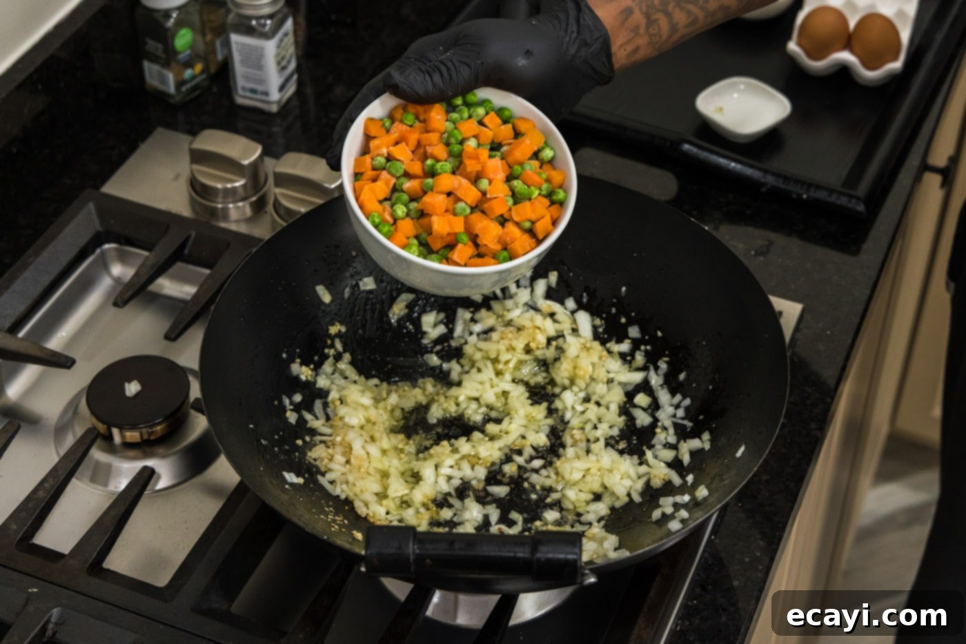 Golden Shrimp Fried Rice 8 adding frozen peas and carrots to a wok with onion and garlic
