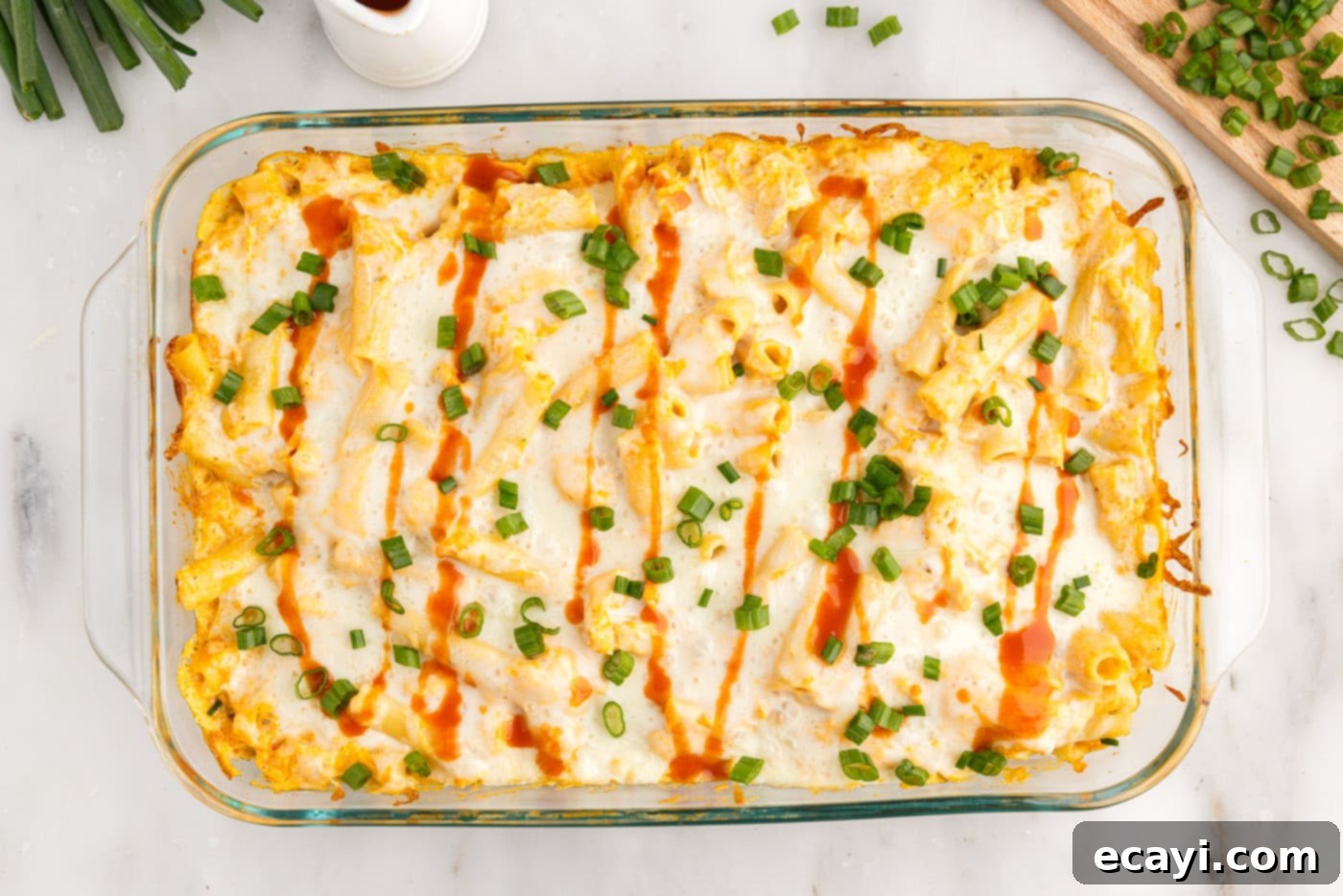Fiery Chicken Comfort Bake 13 overhead of buffalo chicken casserole with hot sauce and sliced green onion garnish