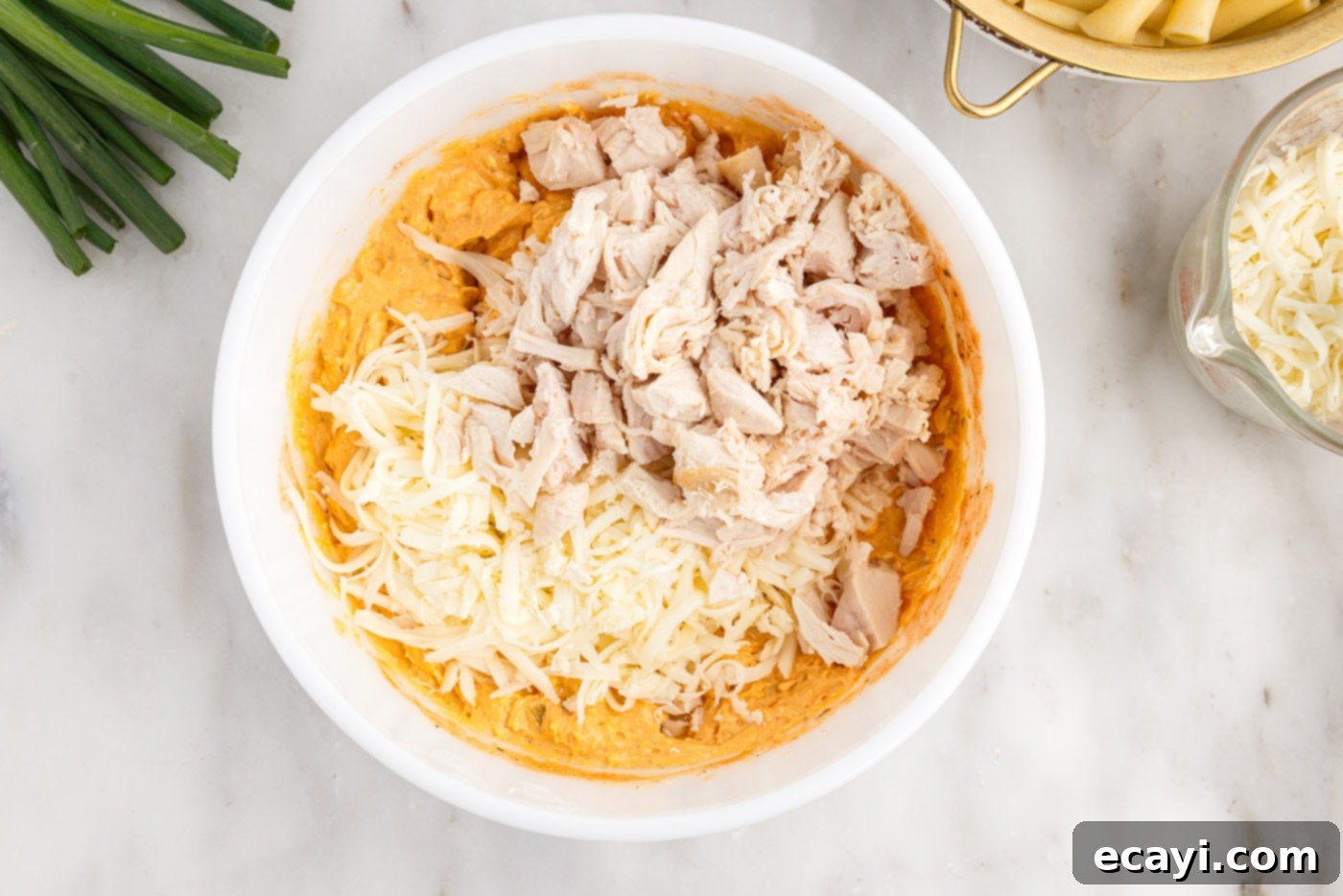 Fiery Chicken Comfort Bake 7 adding shredded cheese and chicken to buffalo chicken mixture