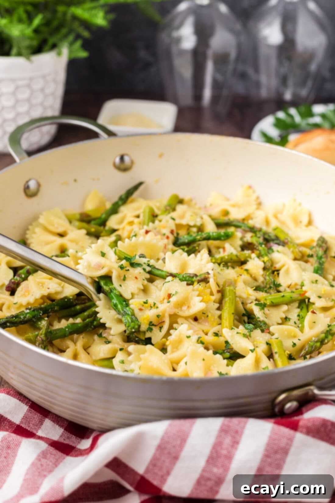 Bright Asparagus Pasta 12 A serving spoon in a skillet full of creamy Lemon Garlic Butter Asparagus Pasta, ready to be served.