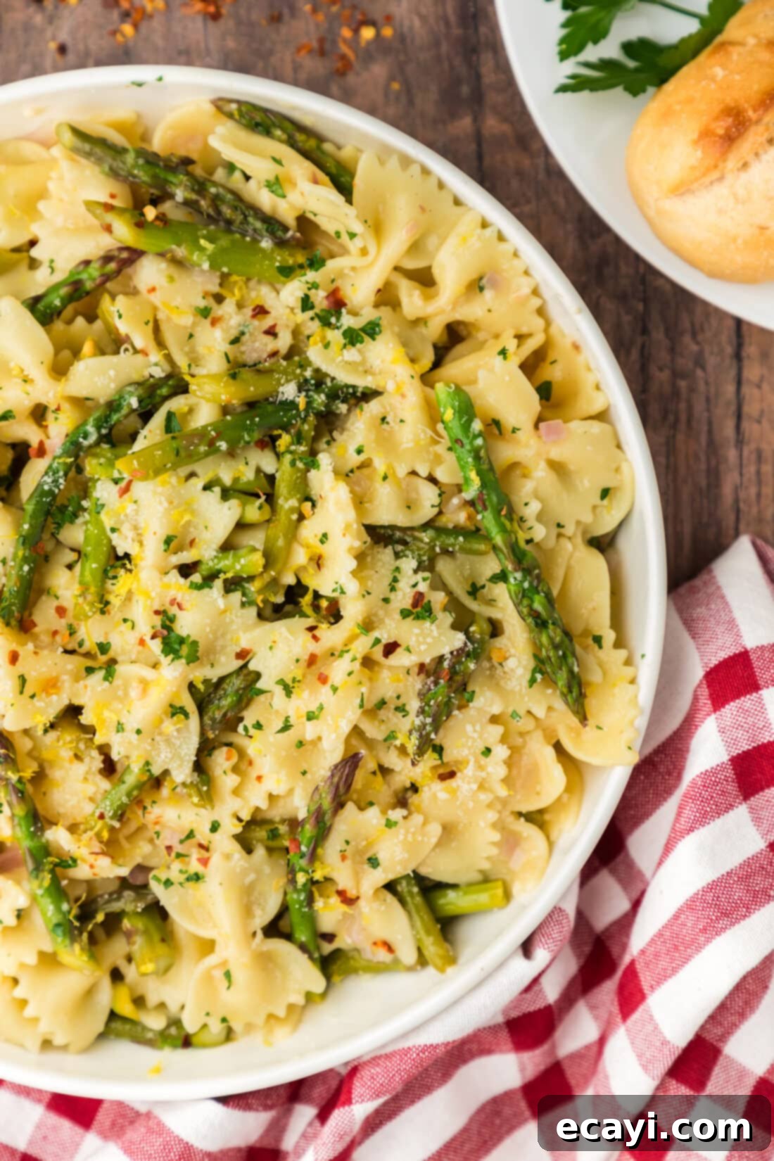 Bright Asparagus Pasta 3 Close up photo of a half bowl of Asparagus Pasta garnished with fresh lemon zest and red pepper flakes, showcasing the delicate bowtie pasta and green asparagus spears.