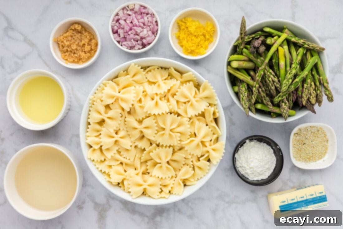 Bright Asparagus Pasta 4 A flat lay photo showing all the ingredients for Asparagus Pasta: bowtie pasta, a bunch of asparagus, lemons, butter, garlic, shallots, white wine, and cornstarch.