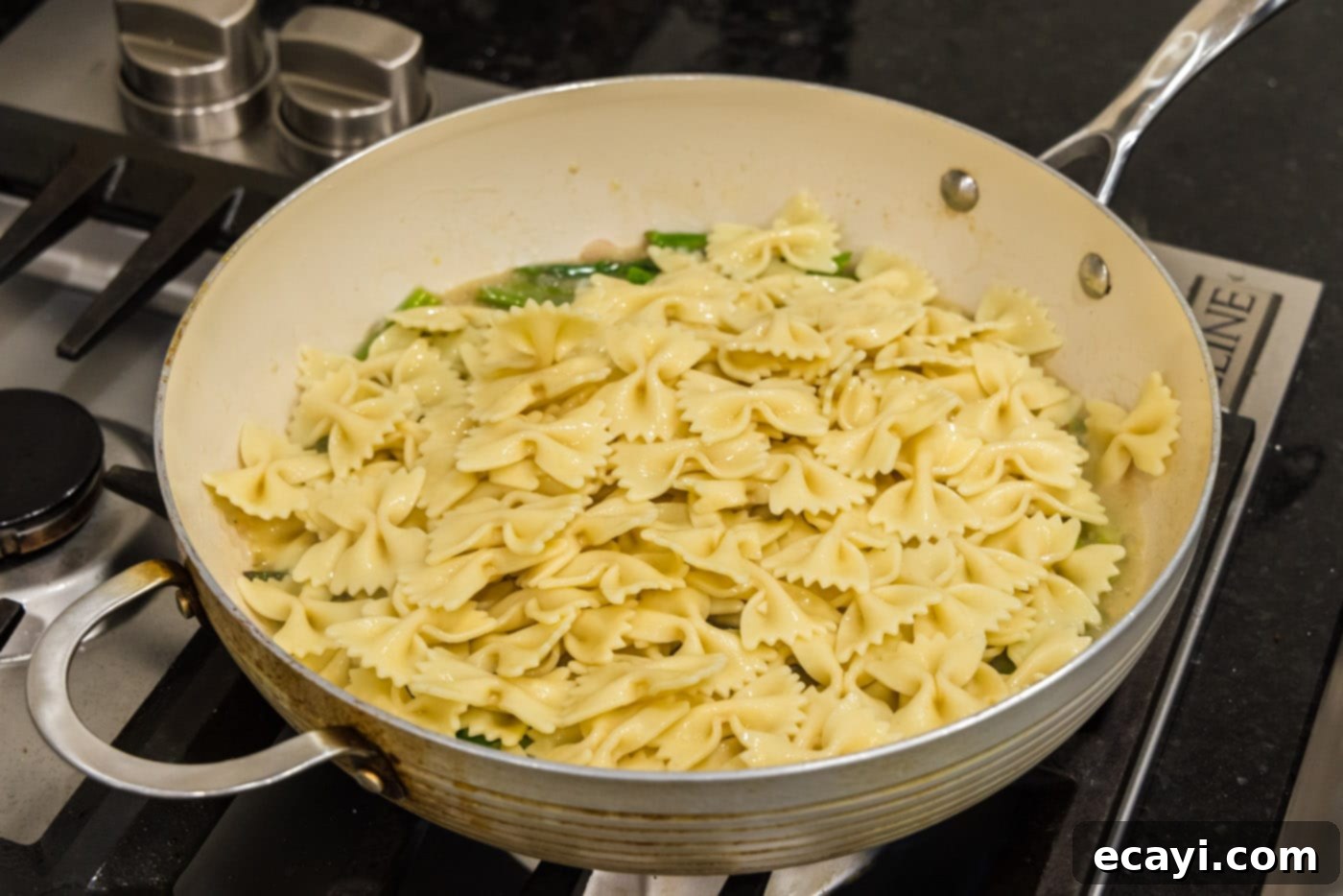 Bright Asparagus Pasta 9 Cooked bowtie pasta added to the buttery asparagus sauce in a skillet, ready to be tossed.