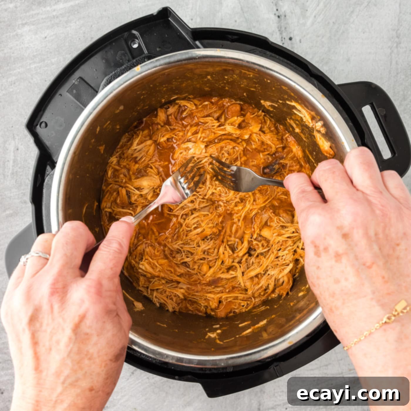 Tender Instant Pot BBQ Chicken 11 Shredding tender barbecue chicken directly in the Instant Pot with two forks.