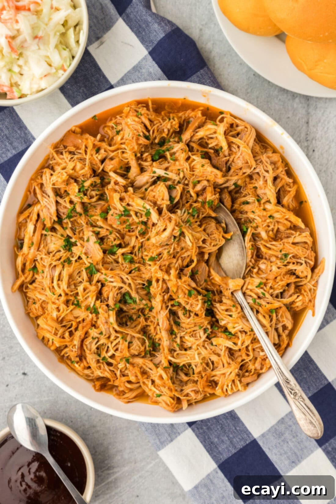 Tender Instant Pot BBQ Chicken 12 Overhead photo of a bowl of Instant Pot BBQ Chicken with a spoon, highlighting its inviting texture and saucy goodness.