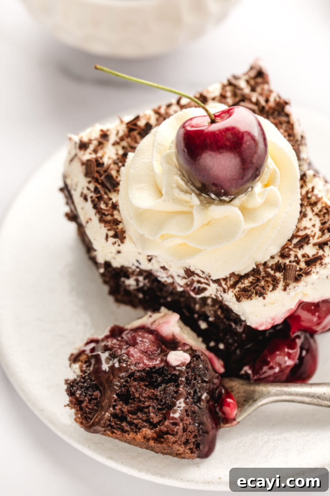 Decadent Black Forest Poke Cake 14 Piece of Black Forest Poke Cake on a plate with a bite removed on a fork