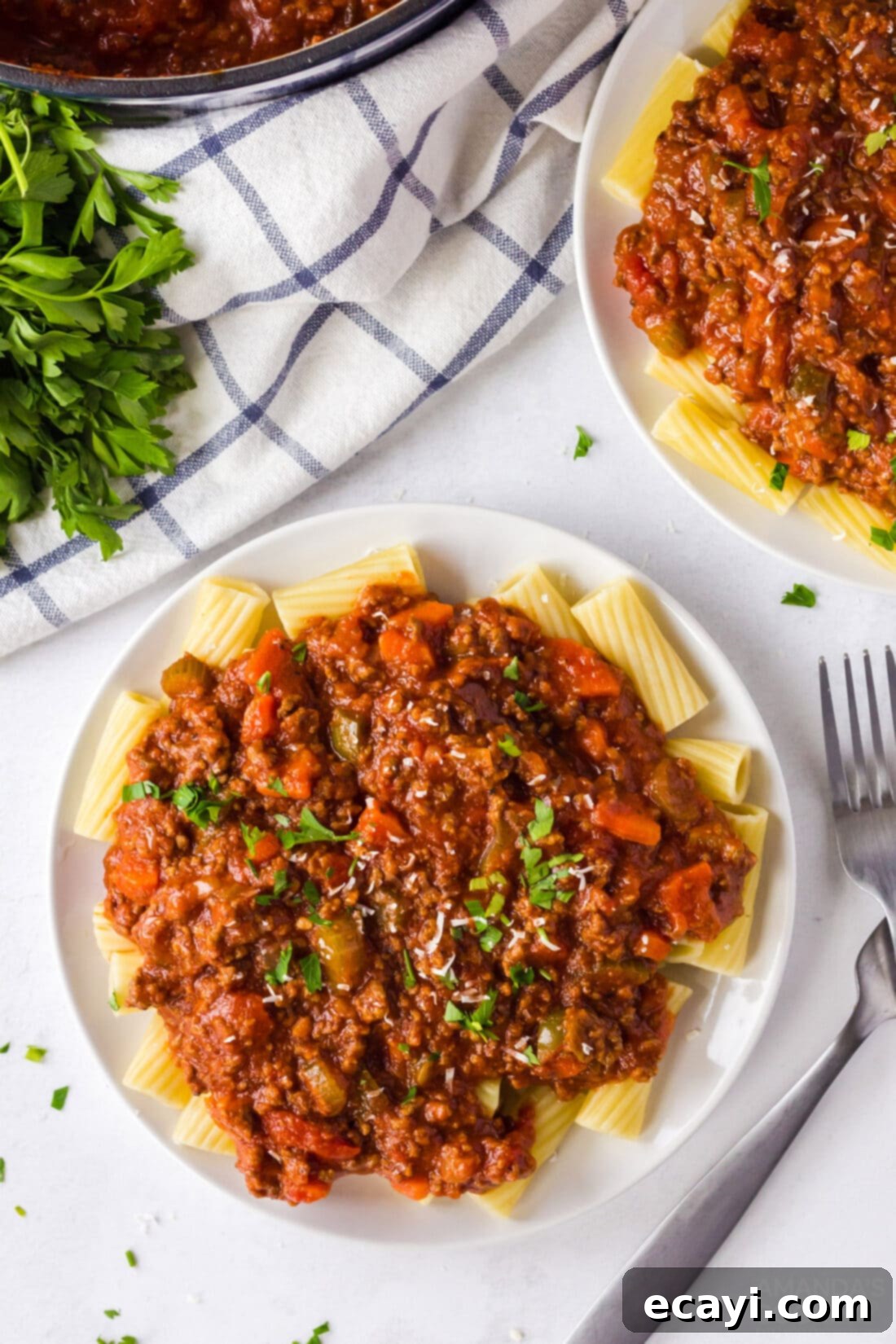 Hearty Bolognese Ragù 3 A serving of broad pasta noodles generously topped with homemade Bolognese sauce and a sprinkle of fresh Parmesan cheese.