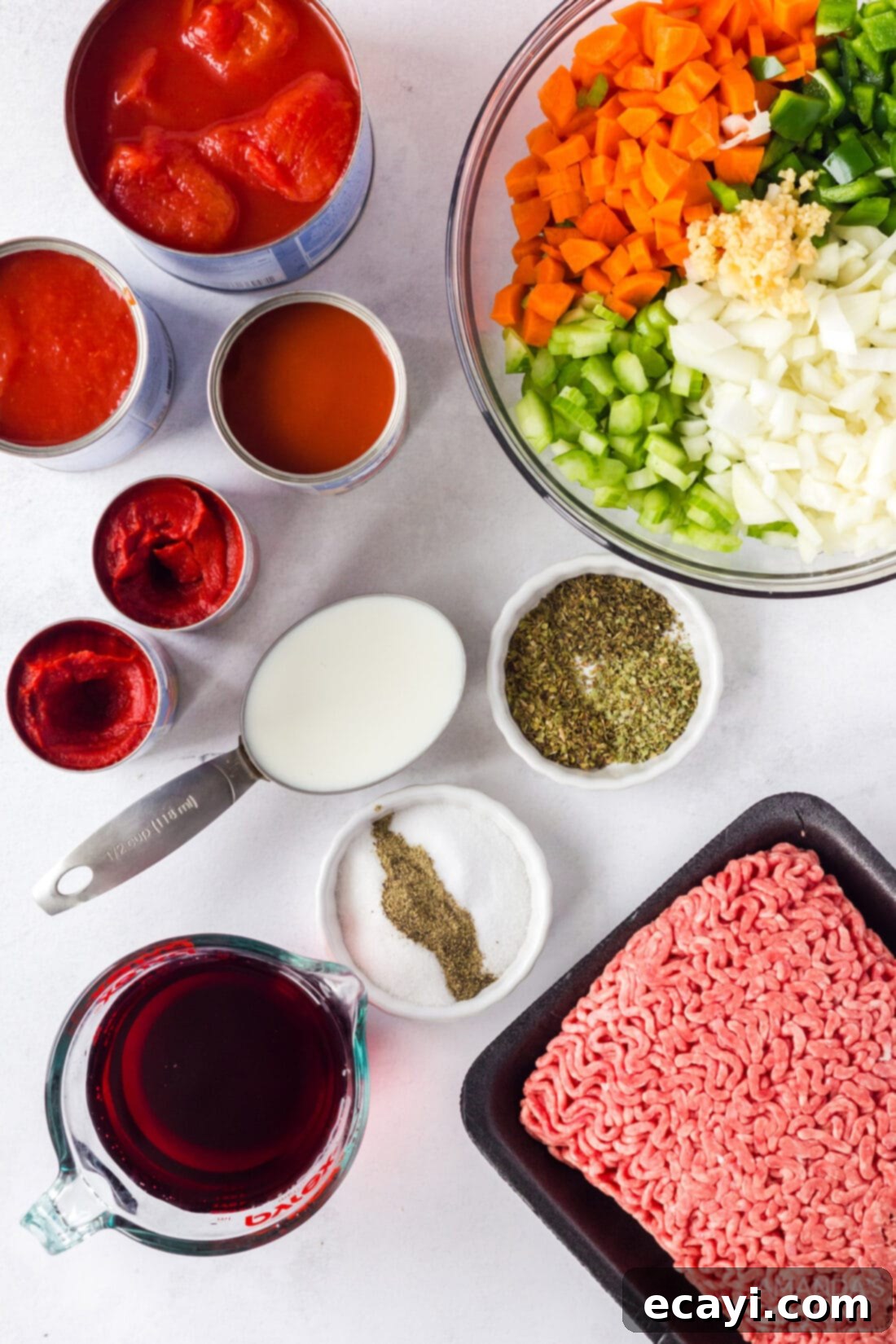 Hearty Bolognese Ragù 4 A collection of fresh ingredients laid out for making Bolognese sauce, including ground beef, diced vegetables, and canned tomatoes.