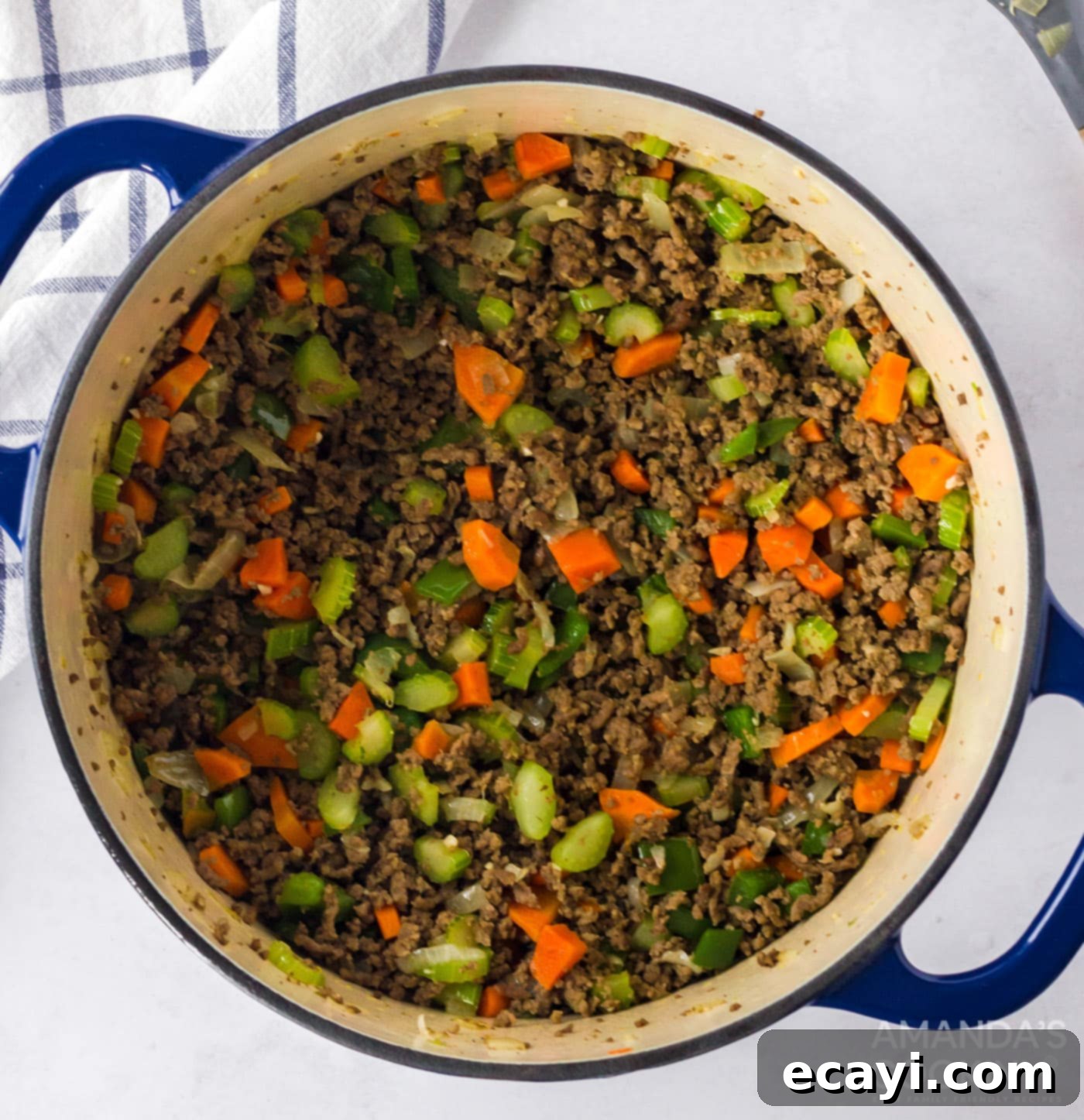 Hearty Bolognese Ragù 6 Finely chopped celery, carrots, onion, green bell pepper, and garlic sautéing with browned ground beef in a large pot.