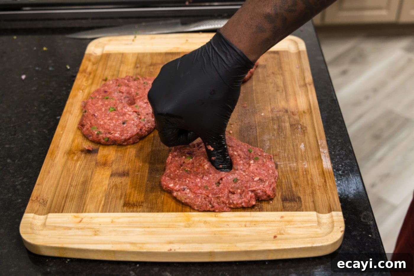 Premium Bison Burger 9 pressing thumb into center of bison burgers