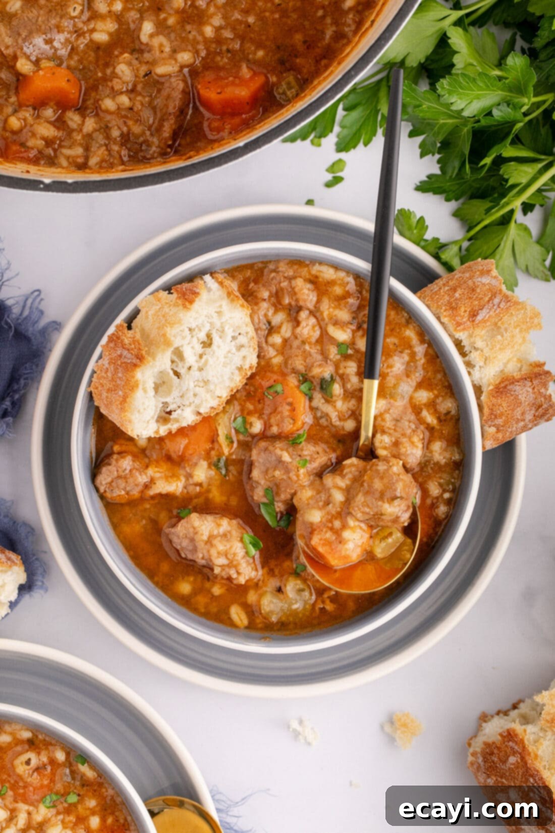Wholesome Beef and Barley Comfort 2 A comforting bowl of beef barley soup, garnished with fresh herbs and a spoon, with a slice of bread beside it.