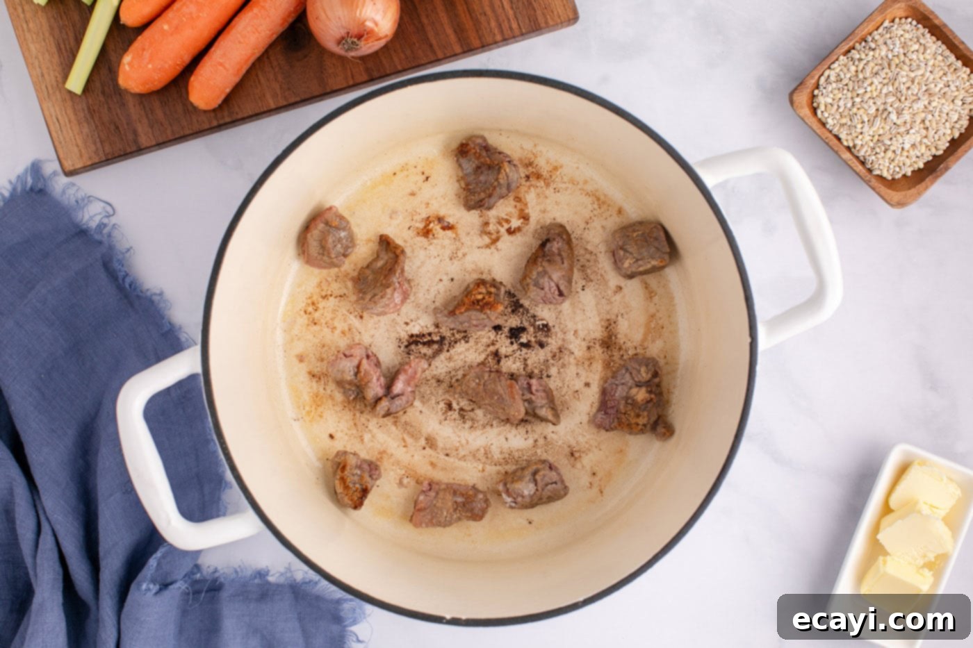 Wholesome Beef and Barley Comfort 7 Searing beef stew meat in a large pot with melted butter to achieve a golden-brown crust.