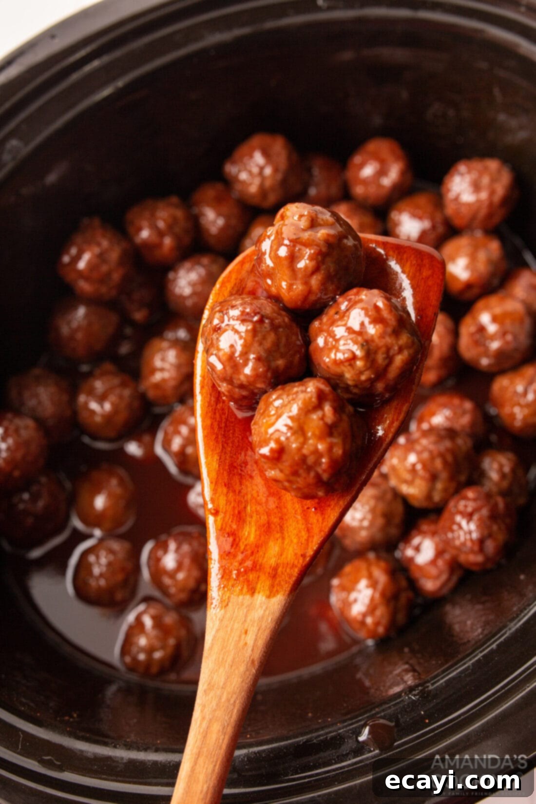 Unlocking Your Slow Cooker 4 A wooden spoon delicately lifting appetizer meatballs from a simmering crockpot, illustrating the effortless serving of delicious small bites.