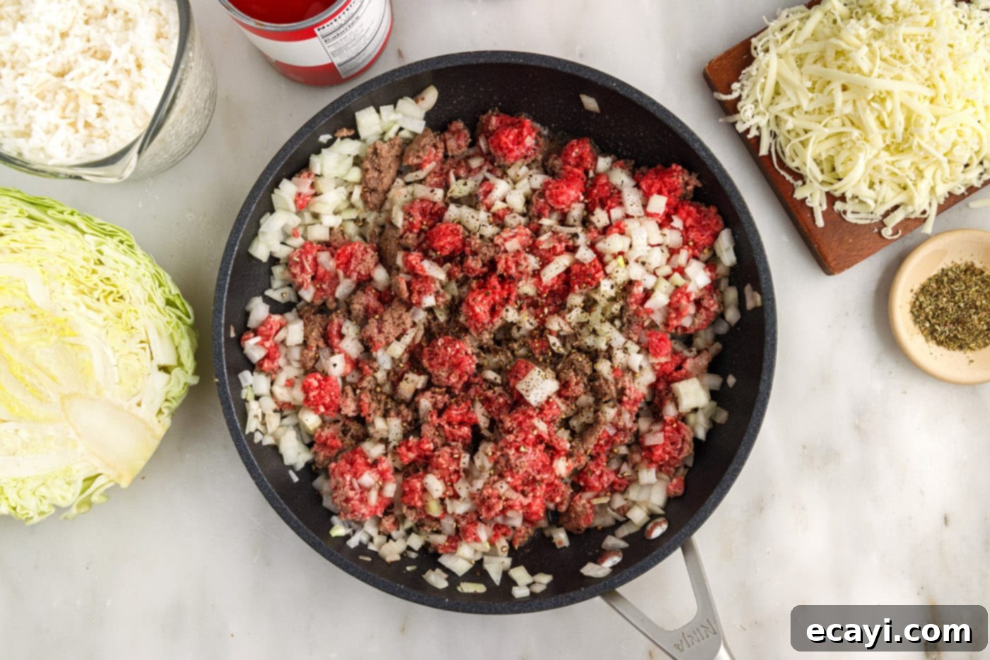 Hearty Cabbage Roll Bake 6 seasonings being added to ground beef and onion in skillet
