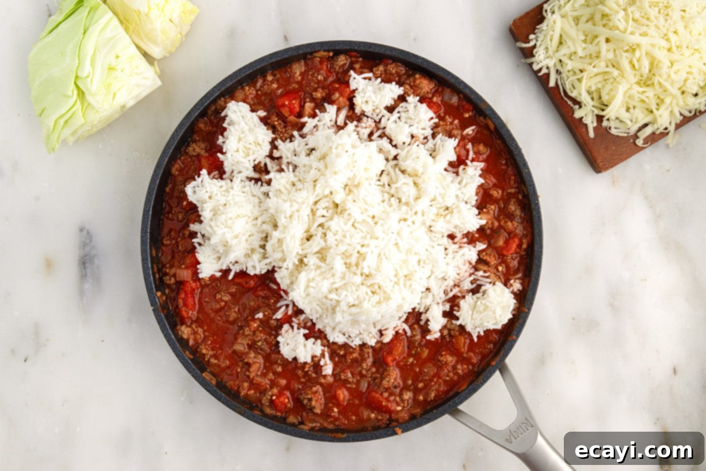 Hearty Cabbage Roll Bake 9 white rice added to skillet with cabbage roll filling, being stirred in