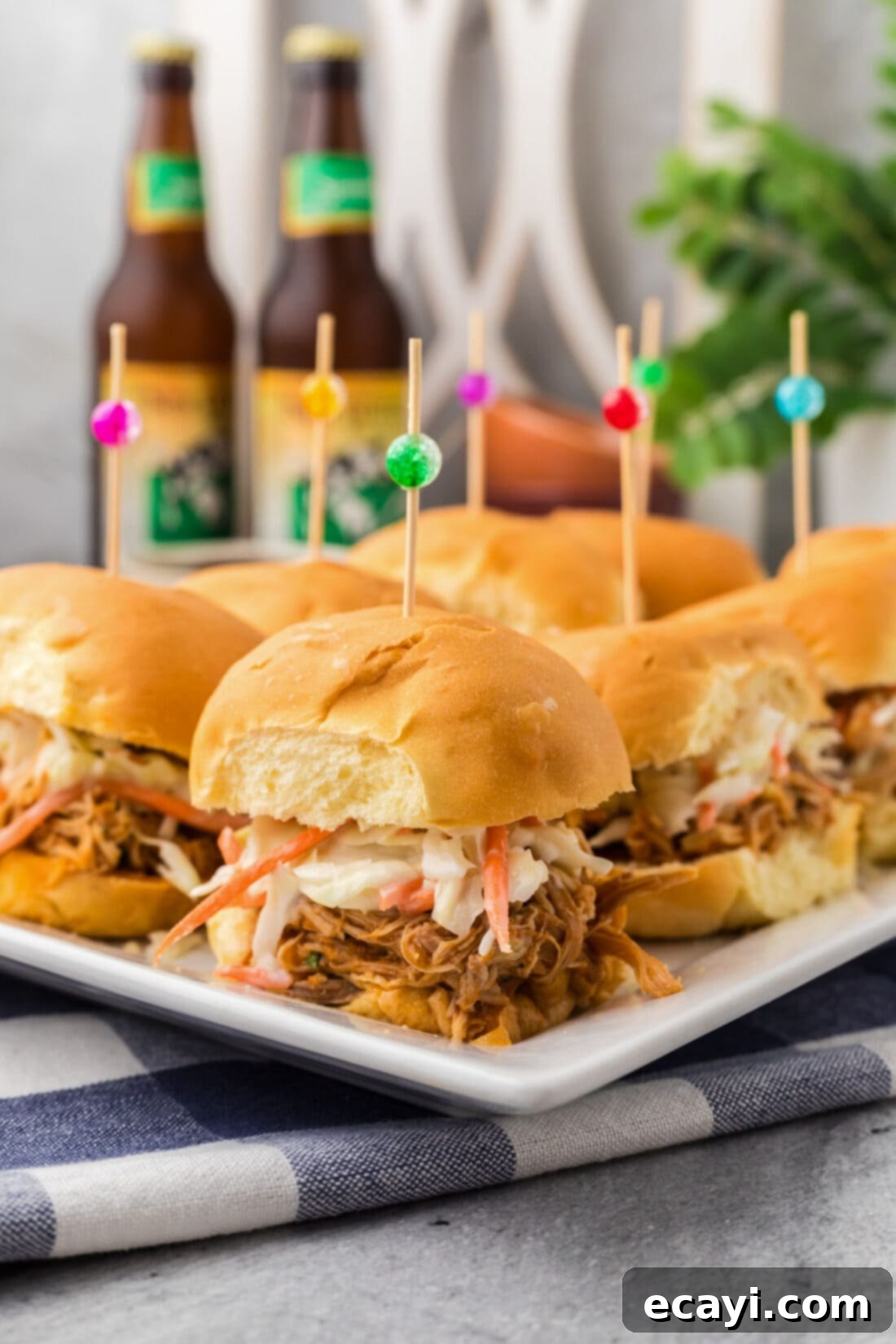 Mini BBQ Chicken Sandwiches 2 BBQ Chicken Sliders on a white platter, showcasing several perfectly assembled mini sandwiches with shredded chicken and soft buns.
