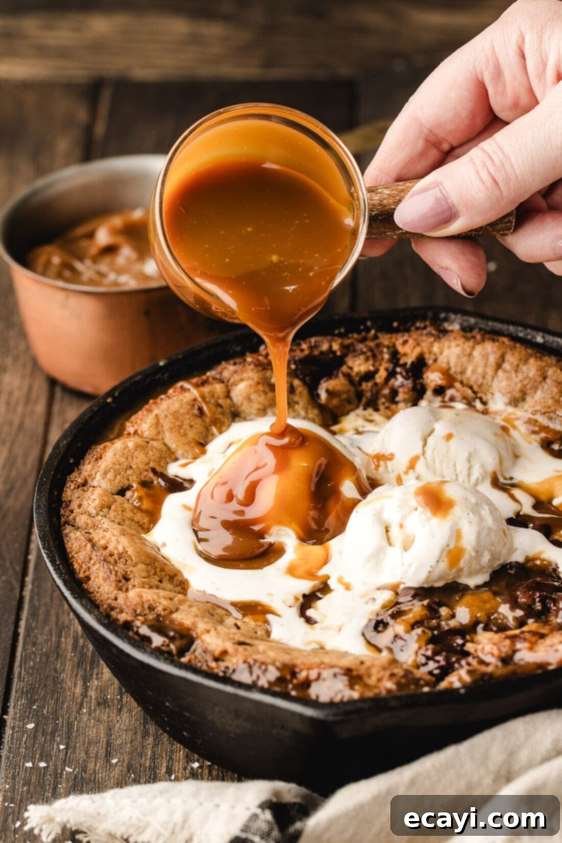 Molten Skillet Chocolate Caramel Cookie 3 Caramel sauce being poured on top of a Chocolate Chip Caramel Skillet Cookie