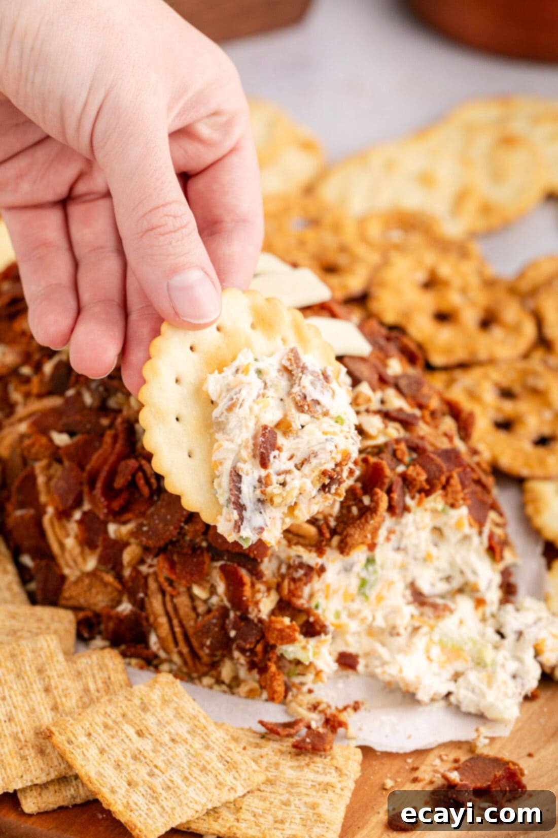 Touchdown Cheese Ball 16 Hand holding a cracker with some cheese on it  from the Football Cheese Ball