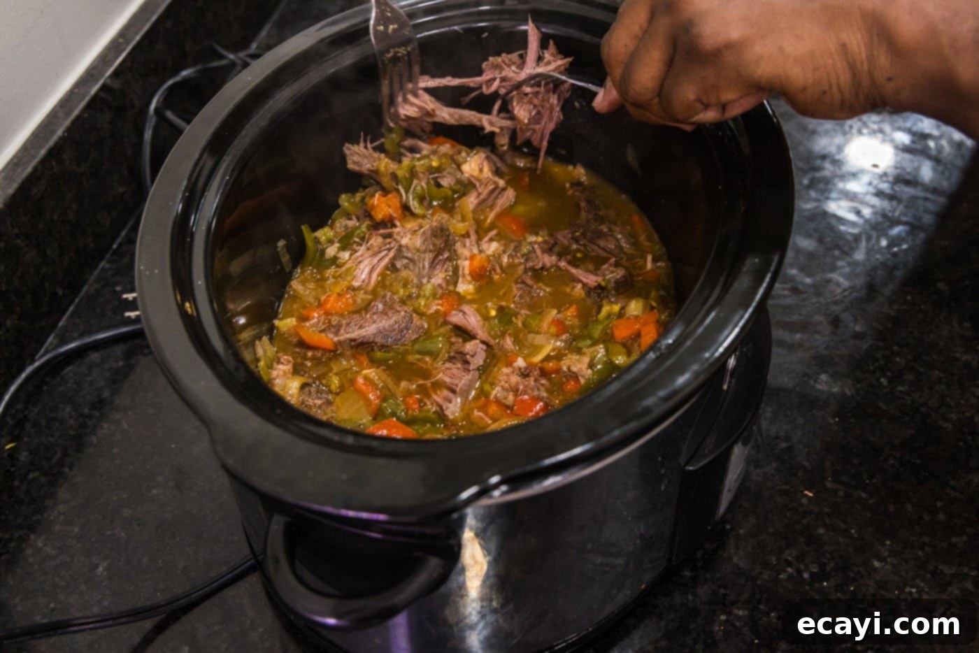 Golden Crispy Beef Carnitas 11 shredding chuck roast in crockpot for beef carnitas using two forks, revealing tender strands of meat