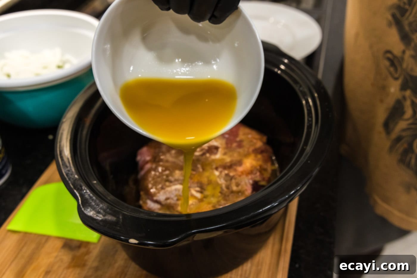 Golden Crispy Beef Carnitas 6 pouring pineapple juice with seasoning over chuck roast in crockpot, ensuring even distribution