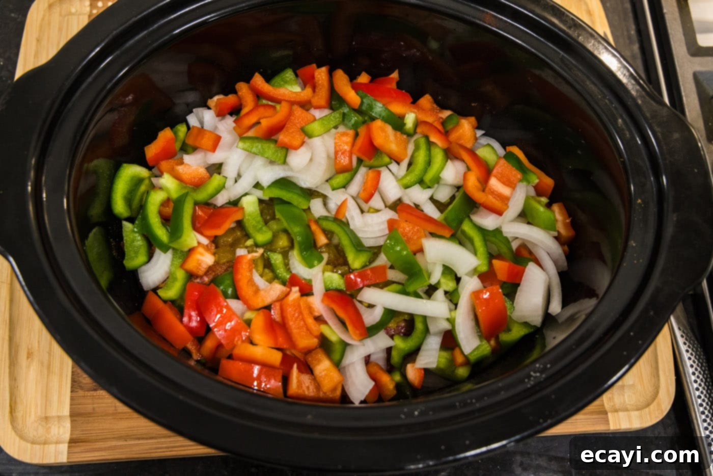 Golden Crispy Beef Carnitas 9 chopped bell peppers and onions on top of chuck roast in crockpot, ready to slow cook into tender perfection
