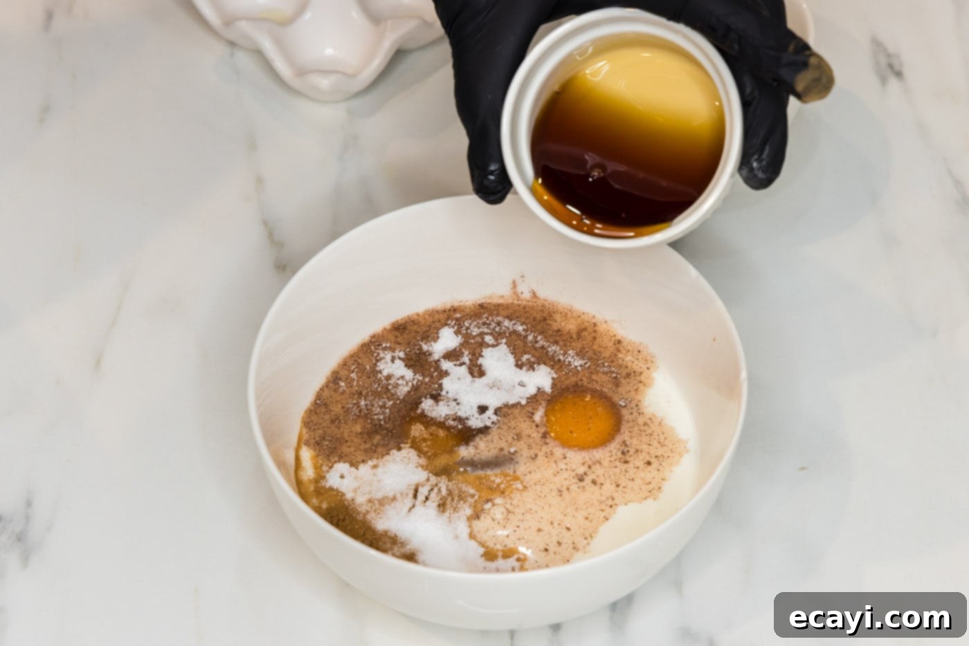Perfect Air Fryer French Toast 5 A hand pouring rich maple syrup into a bowl with French toast batter, emphasizing the creation of the sweet custard.