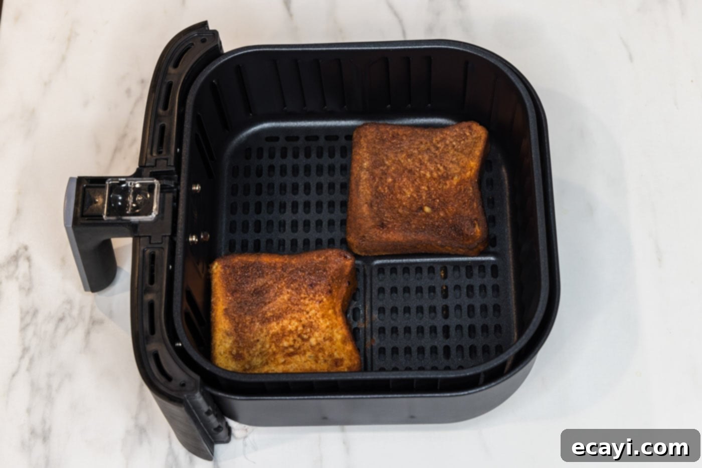 Perfect Air Fryer French Toast 10 Golden-brown, cooked French toast slices in the air fryer basket, showing their perfectly crisped texture.