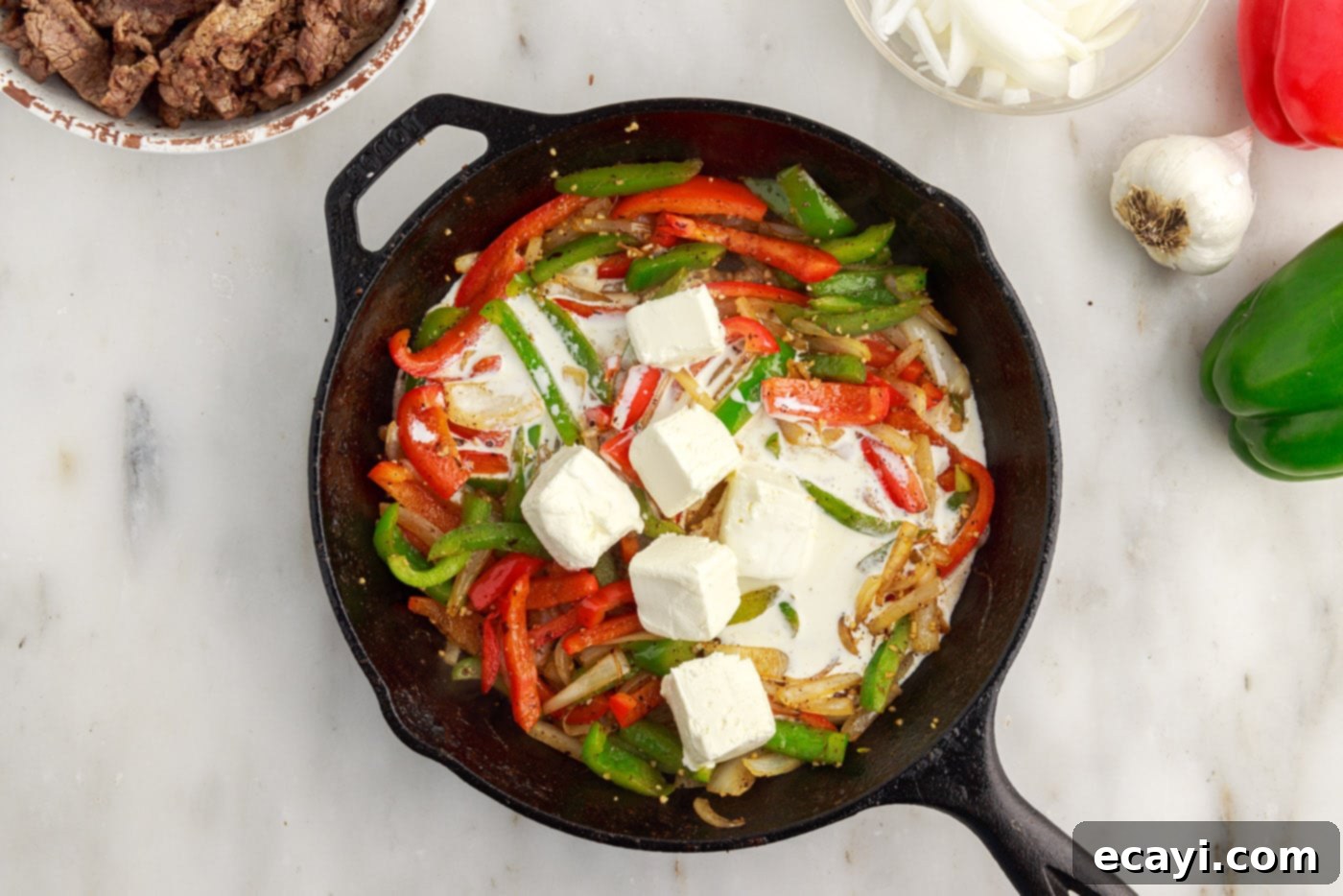 Hearty Philly Cheesesteak Casserole 11 cream cheese and heavy cream added to skillet with bell peppers and onions for casserole