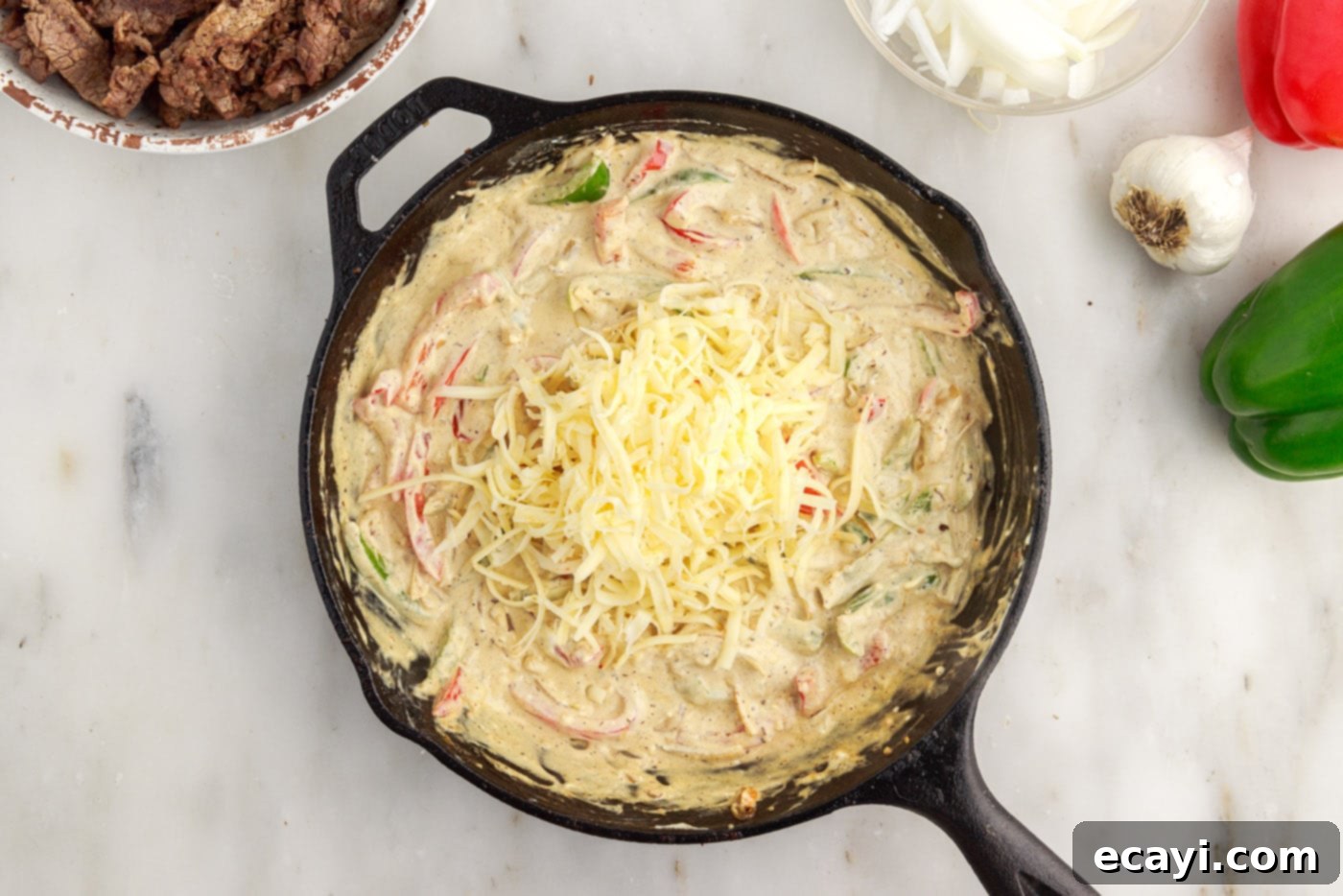 Hearty Philly Cheesesteak Casserole 12 shredded cheese melting into casserole ingredients in a skillet