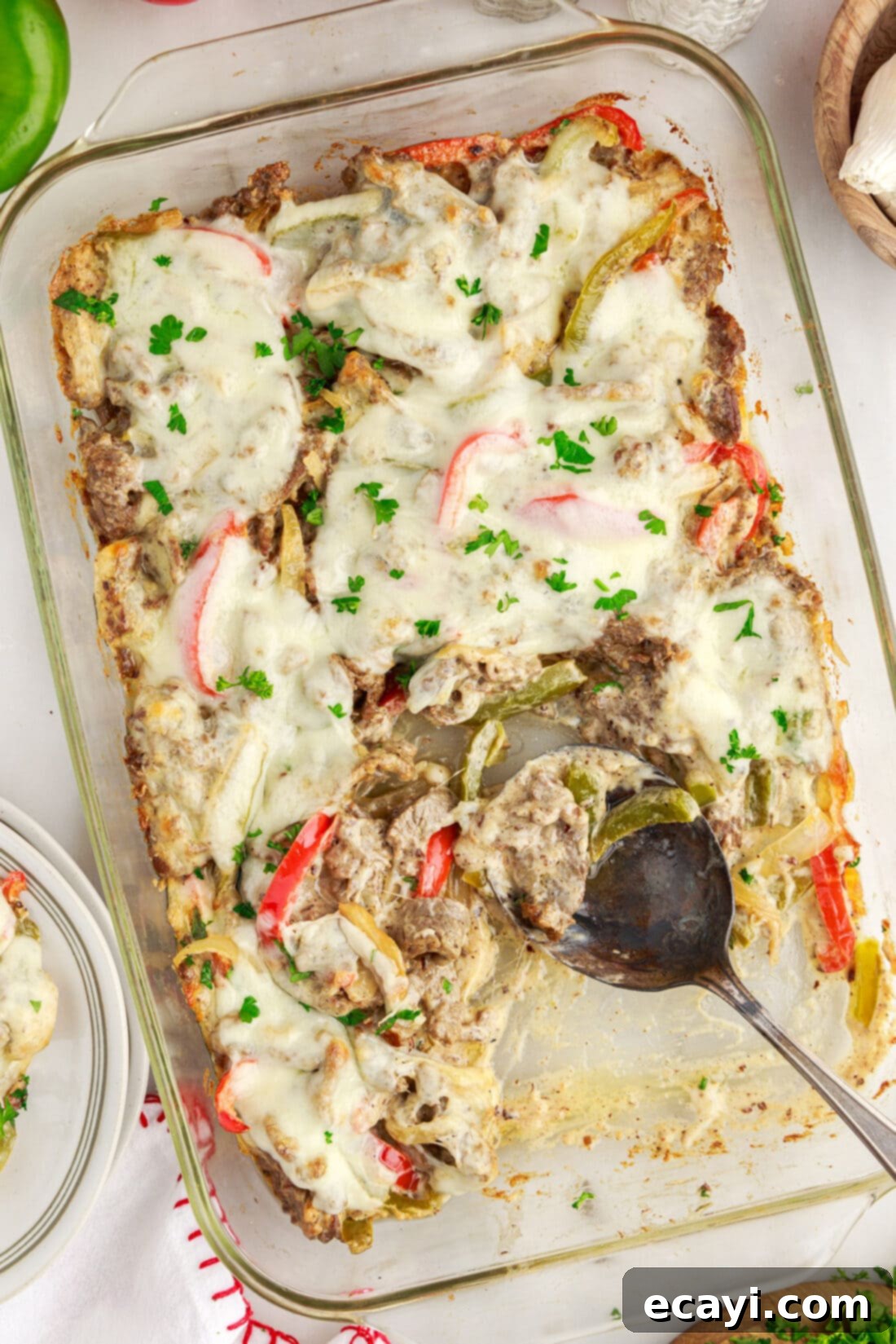 Hearty Philly Cheesesteak Casserole 3 Philly Cheesesteak Casserole with a spoon in it, showcasing melty cheese and tender beef