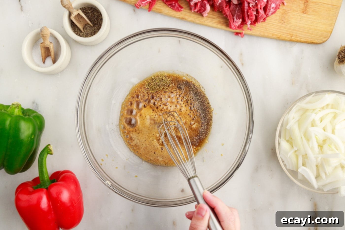 Hearty Philly Cheesesteak Casserole 5 whisking marinade ingredients in a bowl for Philly cheesesteak casserole