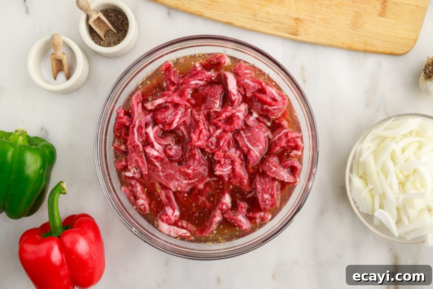 Hearty Philly Cheesesteak Casserole 6 sliced flank steak marinating in a bowl for Philly cheesesteak casserole