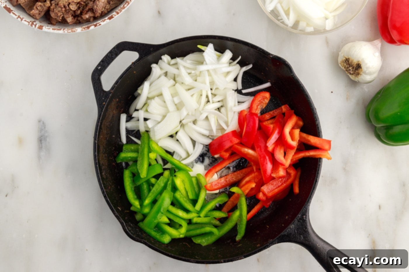 Hearty Philly Cheesesteak Casserole 9 sliced bell peppers and onions sautéing in a cast iron skillet