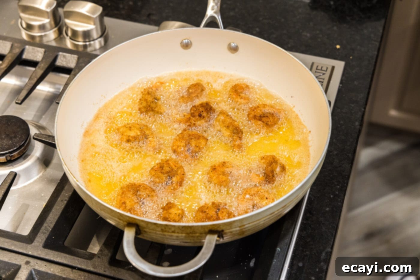 Crispy Fried Shrimp 12 breaded shrimp cooking in oil in a skillet