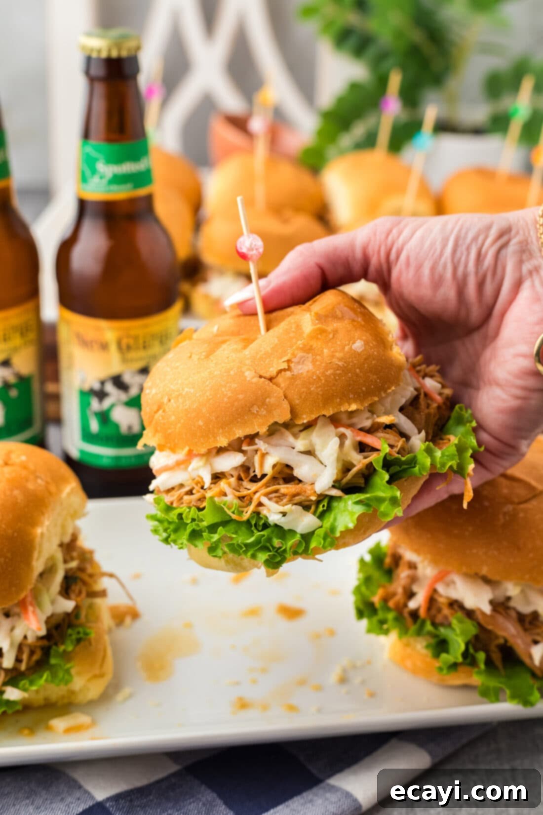 Smoky BBQ Chicken Sandwich 2 Hand holding up a BBQ Chicken Sandwich, showcasing the juicy shredded chicken and fresh toppings.
