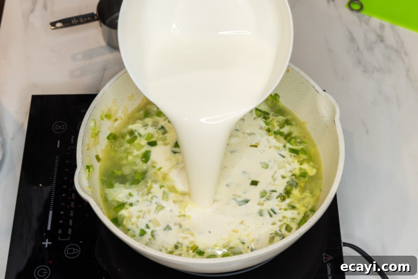 Decadent Lobster Pasta 14 pouring heavy cream into skillet with chopped sauteed vegetables