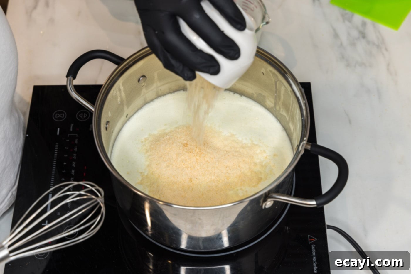 Decadent Lobster Pasta 17 pouring parmesan cheese into pasta sauce in a pot