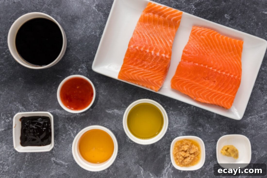Salmon Morsels 4 A flat lay photograph displaying all the fresh and pantry ingredients required for making Honey Soy Salmon Bites, including a salmon fillet, soy sauce, honey, ginger, garlic, hoisin sauce, and sweet chili sauce.