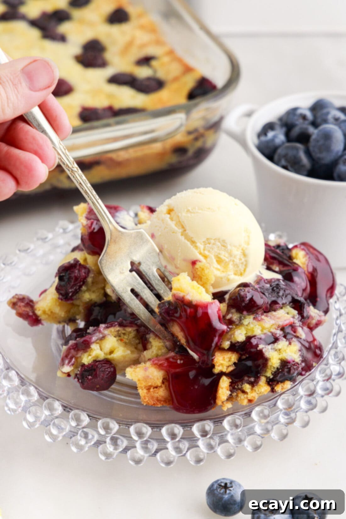 Effortless Blueberry Delight 3 Fork dipping into a serving of Blueberry Dump Cake on a plate