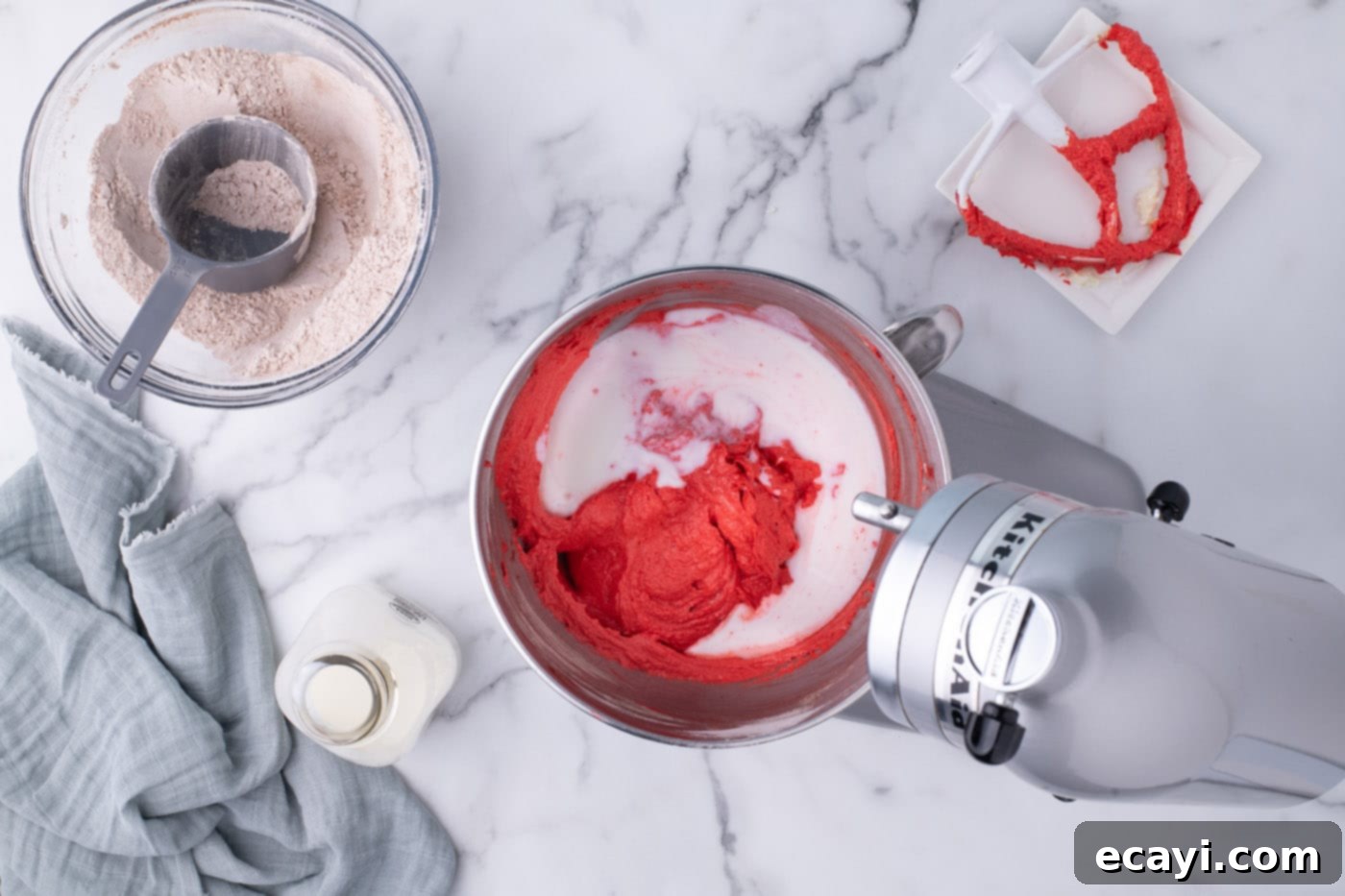 Decadent Red Velvet Treats 12 Pouring buttermilk into the red velvet cupcake batter, alternating with dry ingredients for optimal texture.