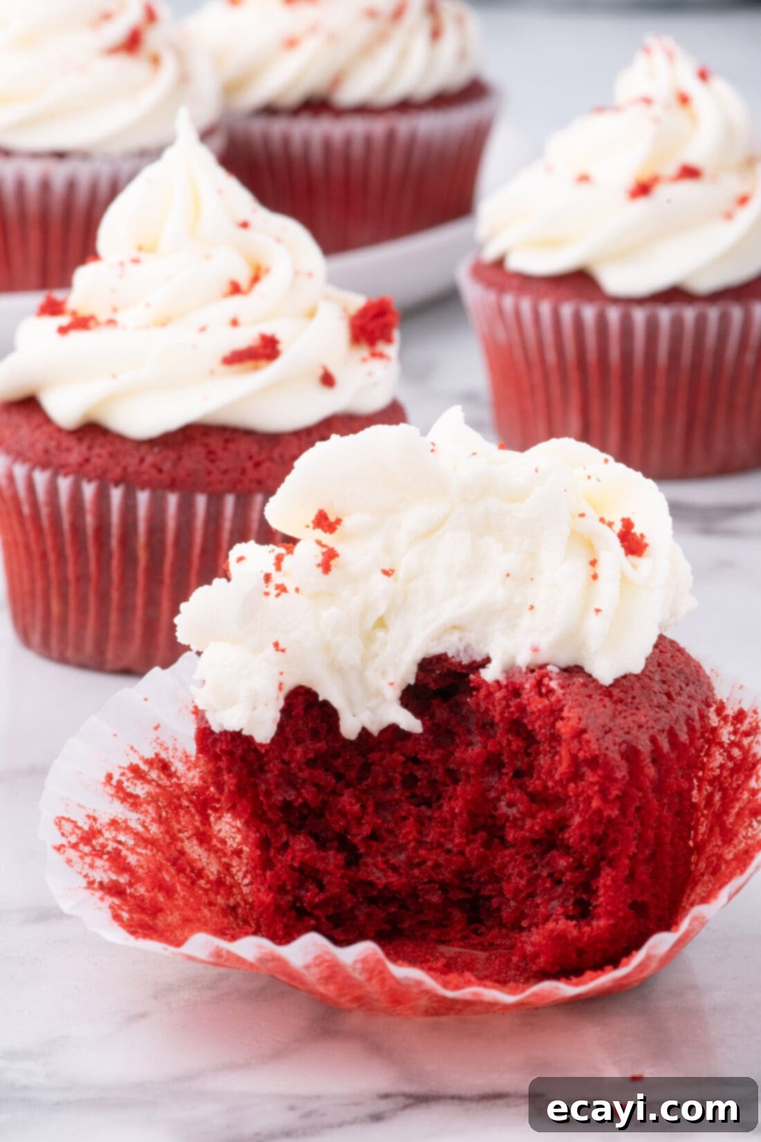 Decadent Red Velvet Treats 3 A perfectly baked Red Velvet Cupcake with a bite taken out, showcasing its moist, red interior and thick cream cheese frosting.
