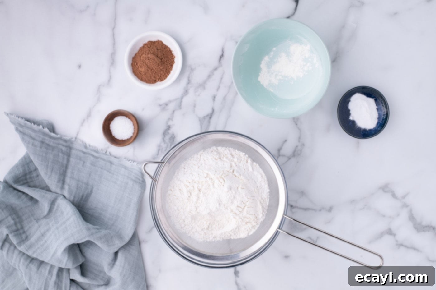 Decadent Red Velvet Treats 5 Sifting dry ingredients like flour, cocoa powder, salt, and baking soda into a large bowl for red velvet cupcakes.