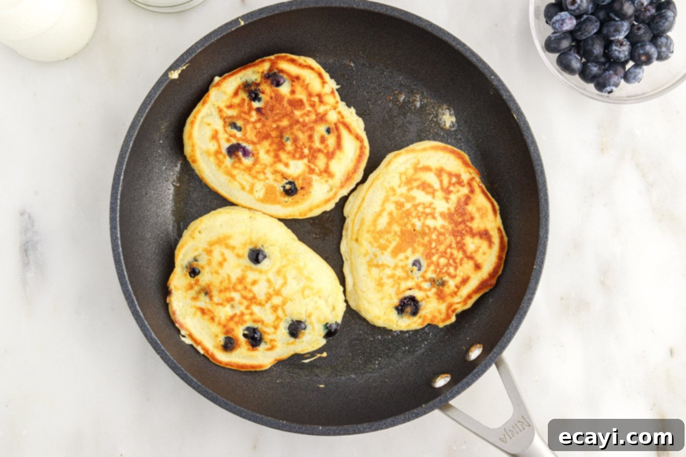 Bursting Blueberry Breakfast Flapjacks 11 cooked blueberry pancakes in a skillet