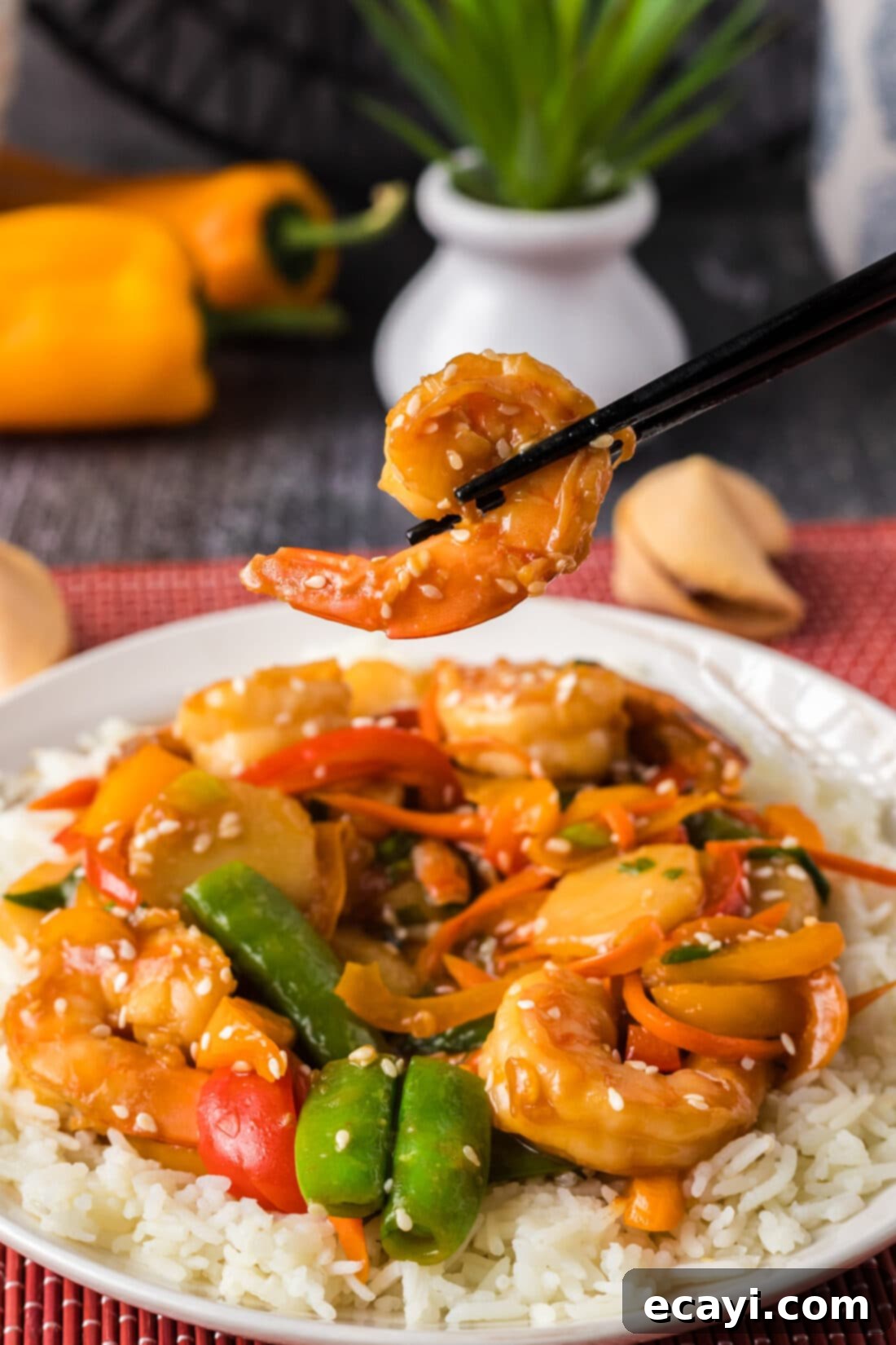 Quickfire Shrimp Stir-Fry 13 Chopsticks holding up a piece of shrimp over a plate of Shrimp Stir Fry, ready to eat
