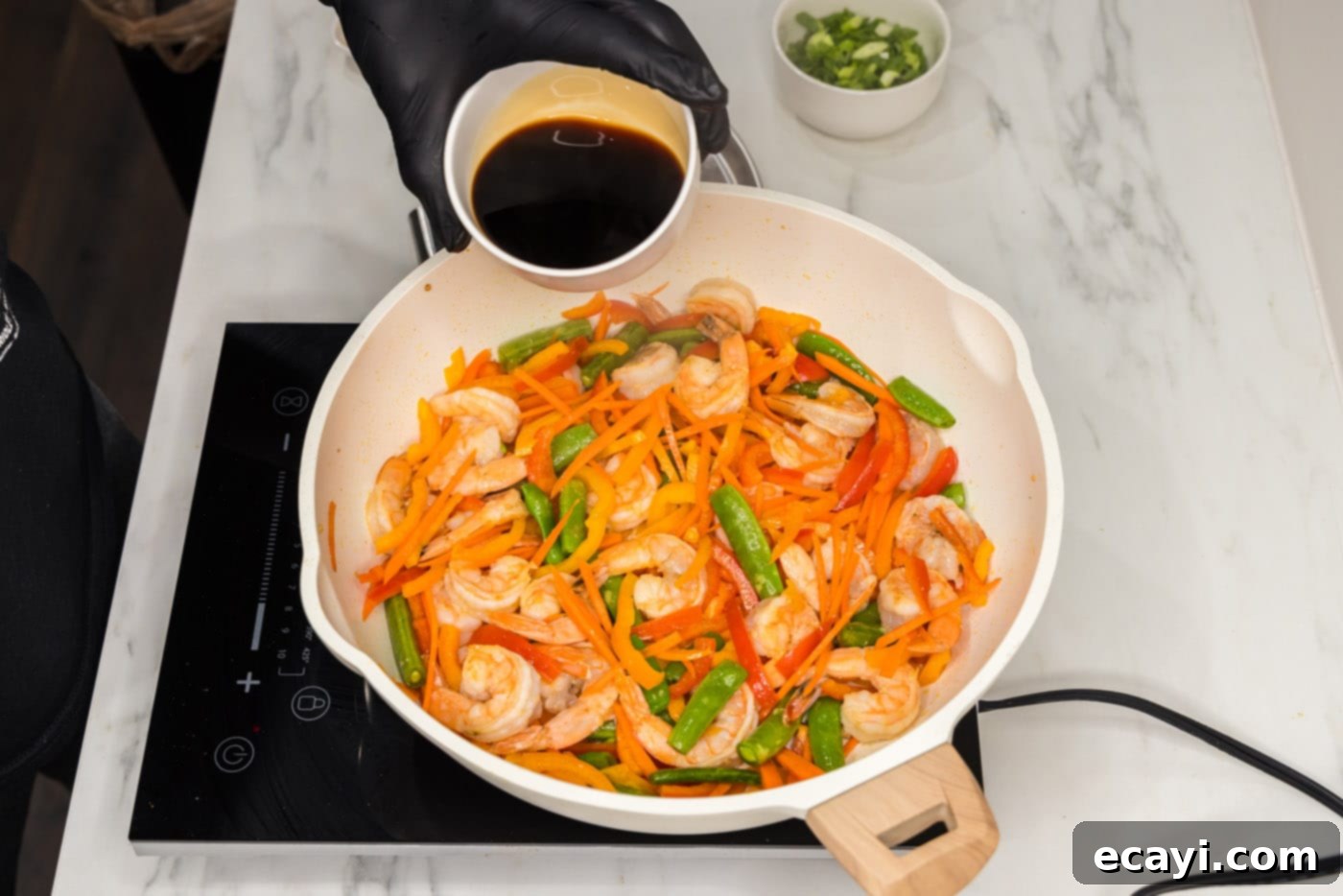 Quickfire Shrimp Stir-Fry 7 pouring soy sauce and other ingredients into skillet with shrimp and vegetables
